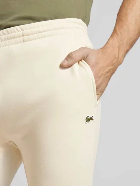 Spodnie dresowe o kroju slim fit z naszywką z logo Lacoste biały